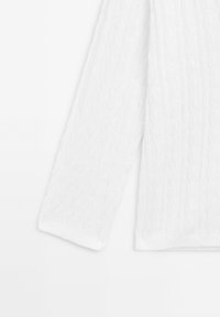 White cable-knit sweater featuring long sleeves, ribbed cuffs, and a textured pattern. The fabric appears soft and lightweight.