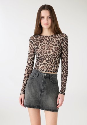 Top a maniche lunghe con stampa leopardata in tessuto leggero e trasparente, abbinato a una minigonna di denim grigio scuro a vita alta con chiusura frontale a bottoni.