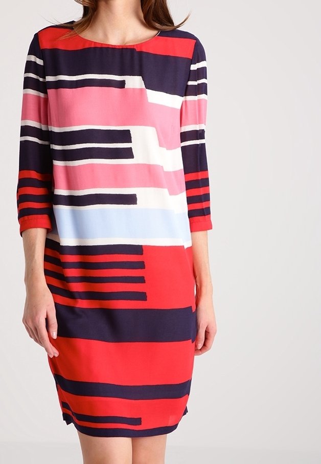 Femme portant une robe longue jusqu'aux genoux à manches longues avec des rayures horizontales audacieuses en rouge, marine, rose, blanc et bleu clair.