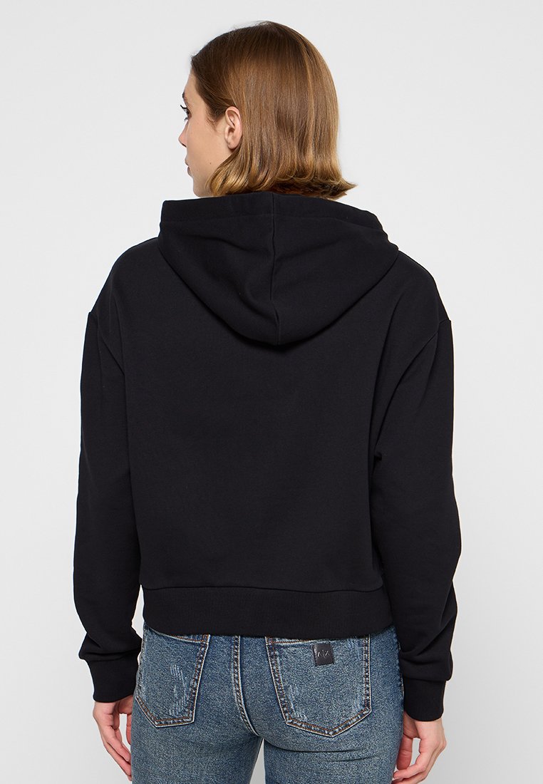 Sudadera corta negra con capucha ajustable, que presenta puños y dobladillo acanalados, hecha de una tela suave. La vista posterior no muestra ninguna marca visible.