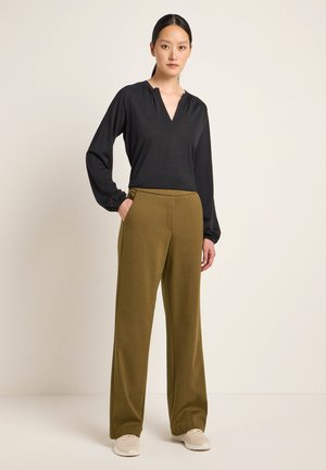 Black long-sleeve top with a V-neck and gathered detail, paired with olive green wide-leg trousers. Both are made of soft, textured fabric.