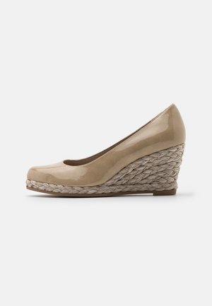 Beige lak kilehæl med flettet rebtekstureret platform og lukket rund tådesign på hvid baggrund.