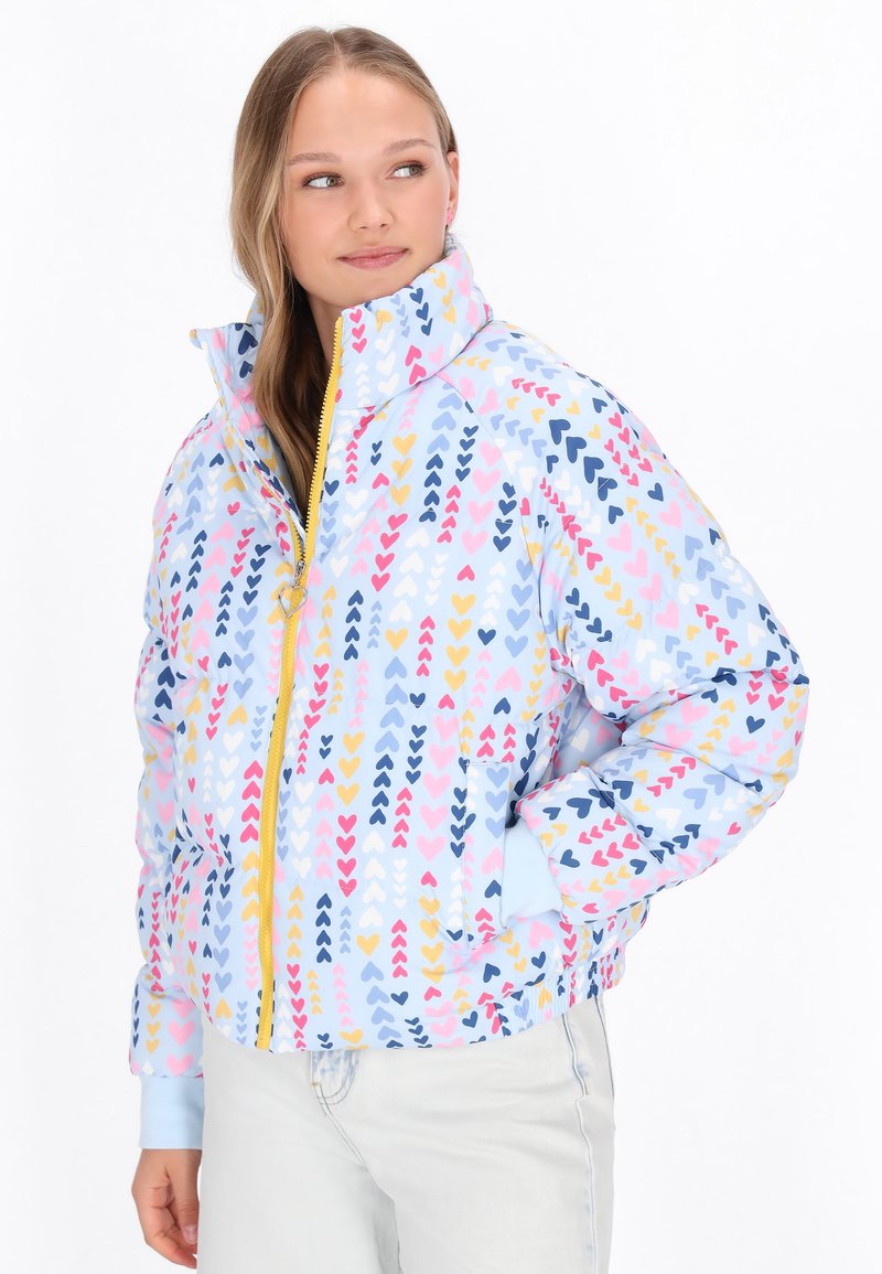 Jachetă căptușită cu o bază albastră, având un model cu inimioare multicolore în nuanțe de roz, galben și bleumarin. Include un guler înalt și închidere cu fermoar.