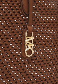 Borsa intrecciata marrone con manico in pelle liscia, caratterizzata da un accento del logo in tono oro e texture intrecciata per un tocco di dettaglio in più.