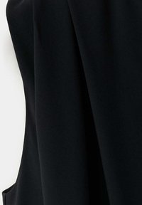 Tissu noir à texture lisse drapé en plis doux sur un fond blanc.
