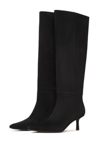 Botas negras de ante hasta la rodilla con una textura suave y punteras puntiagudas, que cuentan con un tacón de aguja delgado y un diseño minimalista.