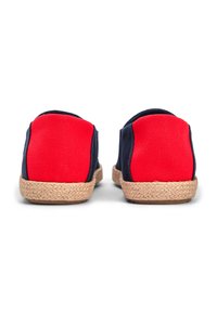 Τα πάνινα παπούτσια slip-on έχουν κόκκινο επάνω μέρος με σκουρόμπλε πλευρές και σόλα καλυμμένη με γιούτα, προσφέροντας υφή και φυσικό φινίρισμα.