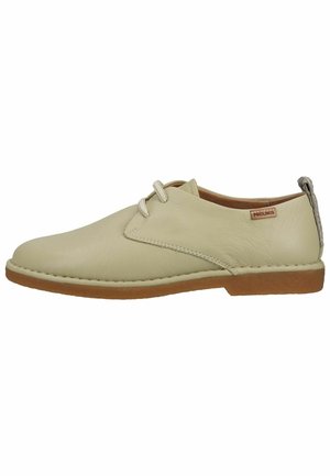 Beige leren casual veterschoen met een bruine zool en een klein merkje aan de zijkant, voorzien van een gevlochten lus bij de hiel.