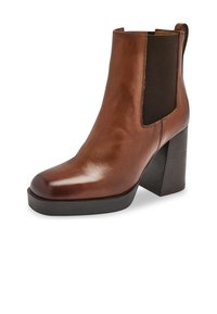 Botín de cuero marrón con tacón cuadrado, paneles laterales elásticos y una textura suave, con un diseño de punta redonda.