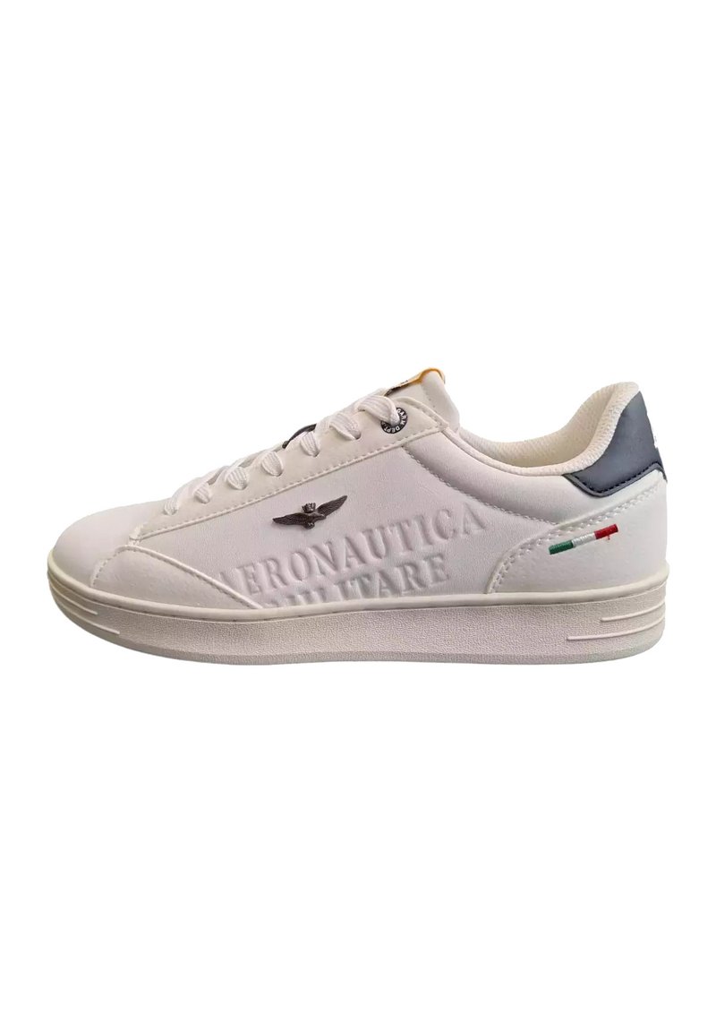 Sneaker bianco con superficie textured, caratterizzato da branding in rilievo, sottili accenti neri e verdi, e design della punta arrotondato.