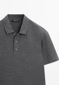 Grå polo i tekstureret stof. Har klassisk krave, tre-knaps åbning og korte ærmer. Subtil meleret mønster.