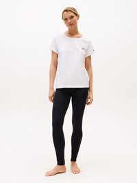 Hvite bomull t-skjorte med rullede ermer, med små svarte bokstaver og logo. Mørk marineblå leggings med en glatt, elastisk tekstur.