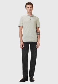 Lys grøn polo skjorte med krave, tre knapper og subtil tekstur. Sammen med sorte lige ben jeans og sorte støvler.