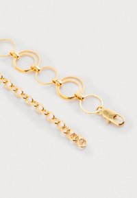 Kultakettinen ranneketju, jossa on suuria pyöreitä linkkejä, pienempiä pyöristettyjä linkkejä ja lukitusyksityiskohta. Sujuva pinta, jossa on heijastava viimeistely.