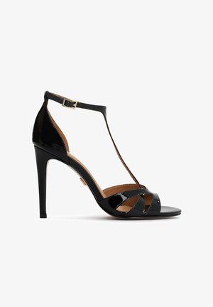 Schwarze Sandalen aus Lackleder mit hohen Absätzen, T-Riemen-Design, verstellbarer Schnalle am Knöchel und offenem Zehenbereich, mit sich kreuzenden Riemen.