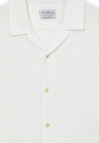 Camicia bianca in lino con un taglio morbido, caratterizzata da un colletto a scollo a V, tre bottoni e un tessuto testurizzato. L'etichetta riporta "CALLIOPE, L."