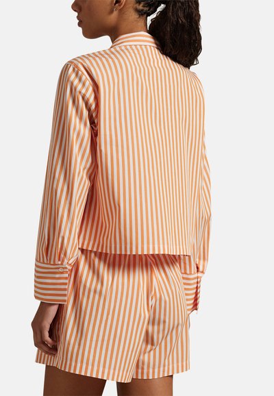 Komplet stroju wypoczynkowego w pomarańczowe i białe paski, składający się z koszuli z długim rękawem i kołnierzykiem oraz szortów. Zawiera detale z guzikami i luźny krój.