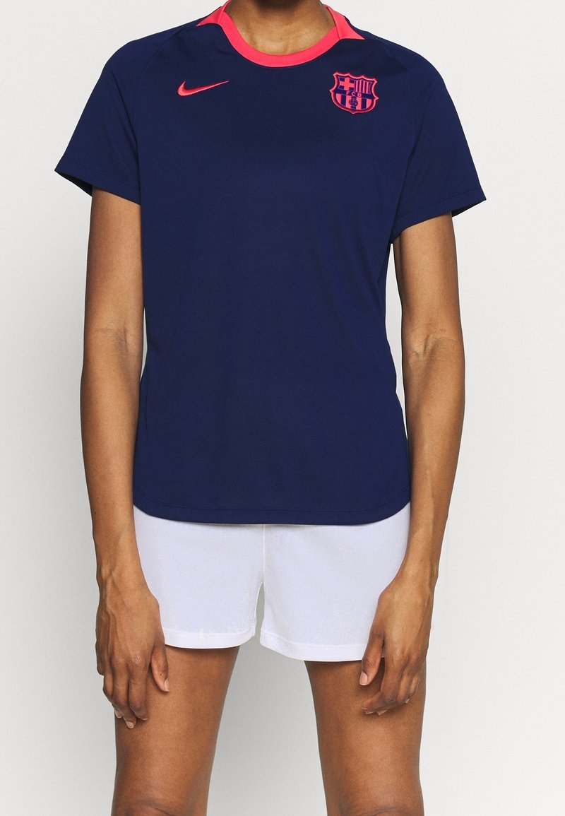 Marinblå Nike fotbollsjacka med rosa krage och detaljer, med Barcelonas klubbmärke på bröstet. Lättviktig, kortärmad design.