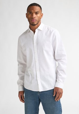 Weißes Hemd aus leichtem Stoff mit klassischem Kragen, langen Ärmeln und lockerem Sitz, kombiniert mit blauen Jeans.
