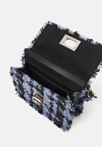 Borsa a tracolla nera e blu con texture, caratterizzata da bordi sfilacciati, chiusura metallica e rivestimento interno nero. Design compatto e angolare.