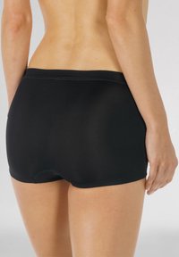 Svarta boxerkalsonger i mjukt tyg. Har en bred midja och benöppningar utan synliga mönster eller dekorationer.