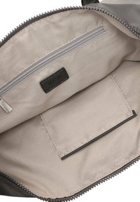 Binnenkant van een grijze tas met een lichtbeige voering, een ritsvak, een label en een plat vak met contrasterende zoomdetails.