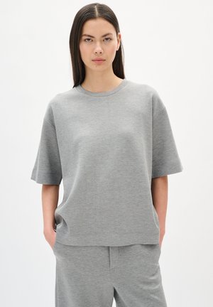 Grå kortærmet sweatshirt med rund hals. Lavet af blødt materiale, med en afslappet pasform og minimale sømme, parret med matchende bukser.
