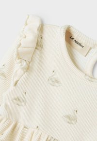 Krémové žebrované dětské šaty s volánkovými ramínky a decentními potisky labutí, se štítkem Lil' Atelier uvnitř výstřihu.