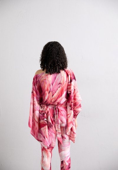 Indumento fluido in un motivo floreale tonale rosa, con design a spalla singola, maniche ampie e dettaglio in vita annodato. Tessuto morbido.