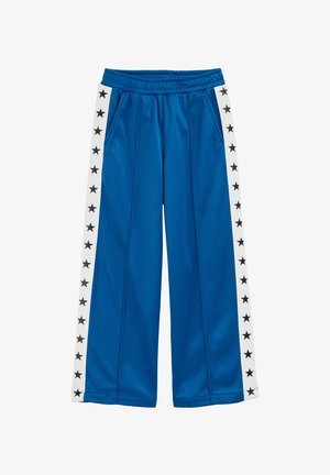 Kék, bő szárú nadrág fehér oldalsávokkal, fekete csillagokkal díszítve, rugalmas derékkal és elülső zsebekkel.