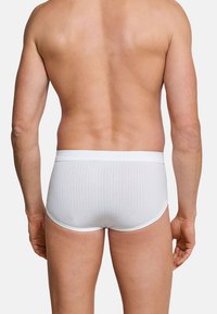 Witte geribde boxershorts met een gladde tailleband en een aansluitend ontwerp, gezien van de achterkant op een blote torso.