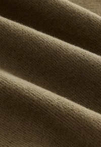 Teksturirana tkanina olivno zelene barve, s rebrastim vzorcem in mehko, puhasto površino. Material deluje topel in prijeten.