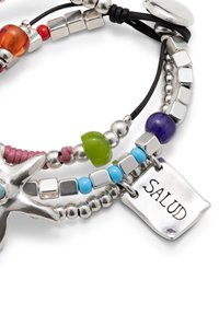 Pulsera de cuentas con cuentas plateadas, verdes, moradas y rojas, un colgante en forma de estrella de mar, y una etiqueta rectangular grabada con la palabra "SALUD."