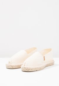 Canvas-Espadrilles in Off-White mit runder Zehenpartie, elastischem Einstieg und einer Jutesohle mit genähten Details entlang der Kante.