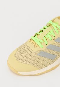 Sneaker giallo chiaro con parte superiore in rete, dettagli argentati e lacci verde brillante. Caratterizzato da una punta arrotondata e una suola testurizzata per una migliore aderenza.