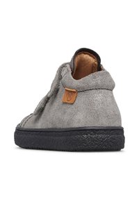 Bottine en daim gris avec semelle en caoutchouc noire, dotée d'un patch en cuir et d'accents cousus. Texture douce et design simple.