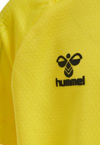 Gul atletisk t-shirt gjord av texturerat tyg, med en svart Hummel-logotyp. Designen inkluderar korta ärmar och ventilerande material.