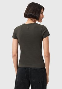 T-shirt fitted verde oliva in cotone, con maniche corte e scollatura rotonda. Dettaglio sul retro con una piccola etichetta vicino al collo.