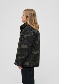 Tarnjacke in Schwarz und Dunkelgrün, mit Knopfverschluss, großen Taschen und hohem Kragen. Strukturierter Stoff, lockere Passform.