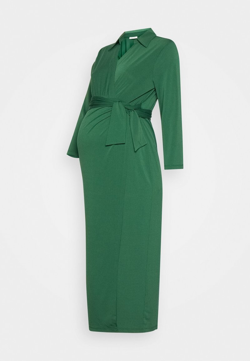 Robe de maternité verte à manches longues avec col et ceinture à nouer, longueur genou, présentée sur un fond blanc uni.