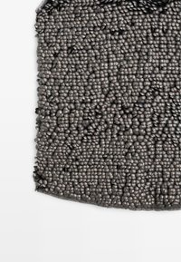 Gestructureerd oppervlak met talrijke afgeronde grijze elementen, dicht opeengepakt. Glad oppervlak met een subtiele glans. Afgeronde rand aan de bovenkant.