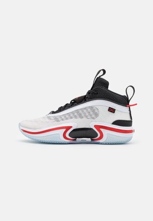 Hvid og sort høj top-sneaker med røde accenter, mesh-overdel, tyk sål og trækflapper på tunge og hæl, vist fra siden.