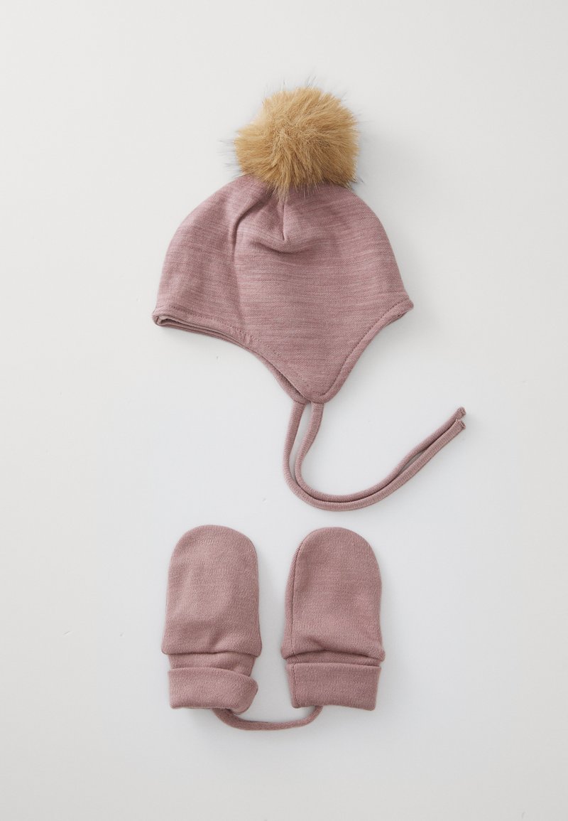 Rosa gestrickte Babymütze mit einem braunen Kunstfell-Pompon obendrauf, kombiniert mit passenden rosa Fäustlingen. Beide bestehen aus weichem, strukturiertem Stoff.