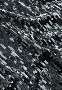 Sort pailletestof med varierende cirkulære pailletformer, der skaber en tekstureret, reflekterende overflade. Glitrende effekt fra lys på pailletterne.