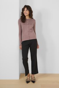 Langarm, mauve ribbed cardigan met een knoopsluiting, gecombineerd met zwarte wijde broek en zwarte puntige slingback hakken.