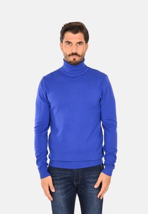 Maglione a collo alto blu realizzato in tessuto lavorato a maglia, con maniche lunghe e polsini e orlo a costine, abbinato a jeans in denim scuro.