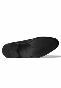 Schwarze Ledersohle mit glatter Oberfläche, strukturiertem Grip-Bereich und eingeprägtem Logo, entworfen mit einer runden Zehenpartie und minimalistischer Form.
