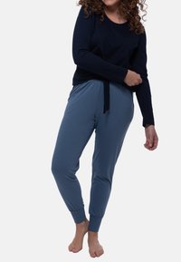 Marinblå långärmad topp i kombination med ljusblå tapered joggers, som har resårmidja och dragsko, tillverkade av mjukt material.