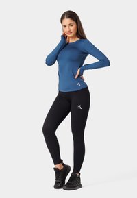 Zils sporta krekls ar garām piedurknēm un caurumiem īkšķiem, apvienots ar melniem ribotajiem legingiem ar logotipu. Strukturēta auduma un pieguļošs dizains.