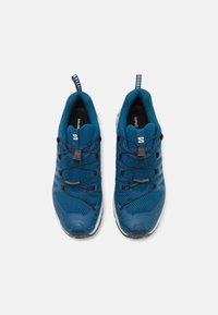 Des chaussures de sport bleues avec une tige en maille, des lacets élastiques et une semelle rembourrée avec une texture pour une meilleure adhérence. Avec un onglet de traction.